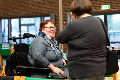 Kvinde i kørestol taler med en anden kvinde.
