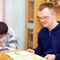 To unge mænd med mentalt handicap, der er i gang med at lave matematik eller lektier 