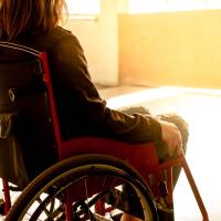 Kvinde uden mulighed for identifikation i kørestol på hospital - set fra ryggen - med et gult skær i fronten af billedet